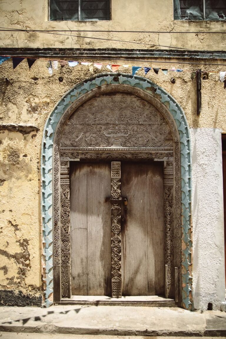 Ornate wooden door in a historical building with intricate carvings and textured facade.