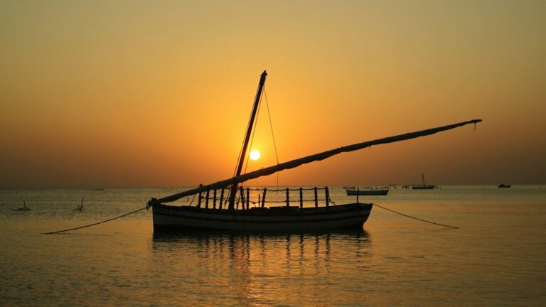Sailboat silhouetted against a warm sunset over the ocean